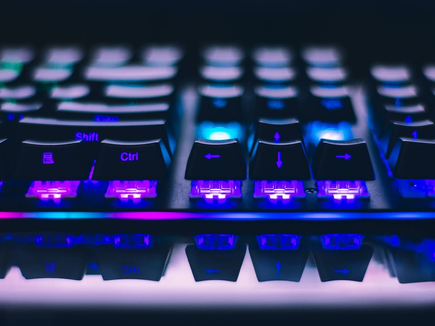 a detailed closeup of illuminated mechanical keyboard keys with focus on blue and purple lights