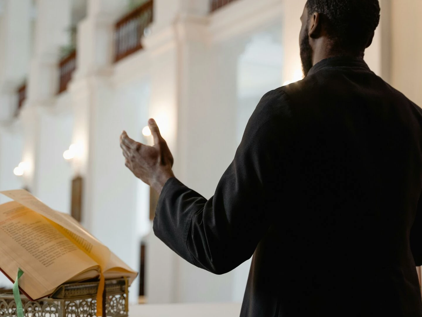 a priest delivers a sermon inside a beautifully lit church standing at an altar
