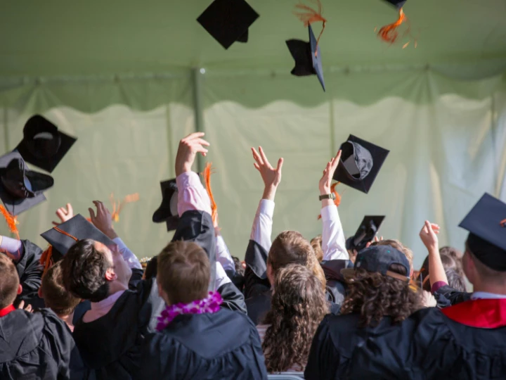 Graduates throw their headwear into the air in celebration