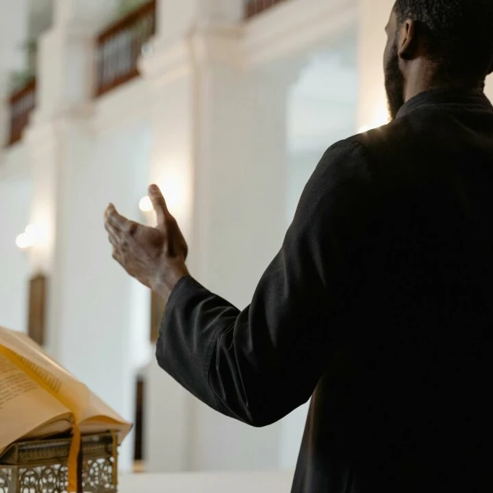 A priest delivers a sermon inside a beautifully lit church, standing at an altar.