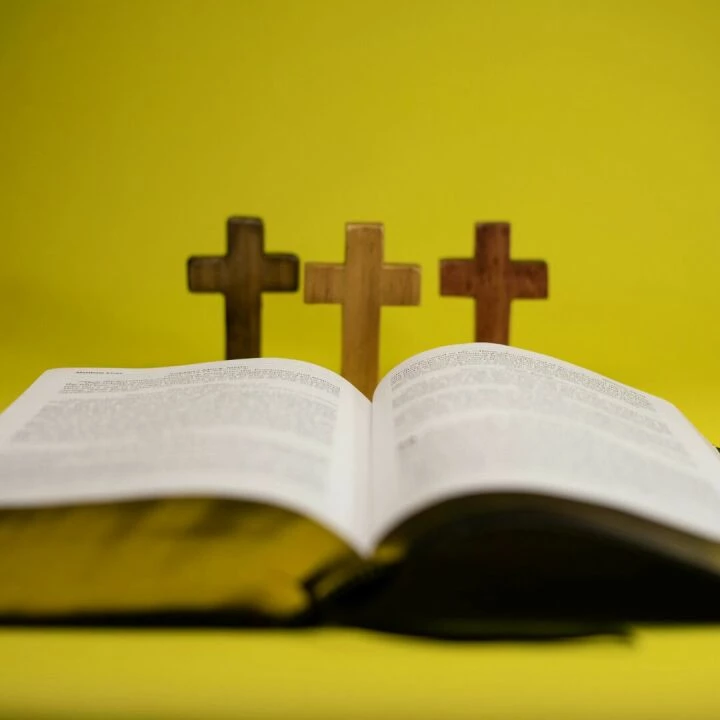 An open Bible with three crosses displayed against a vibrant yellow backdrop.