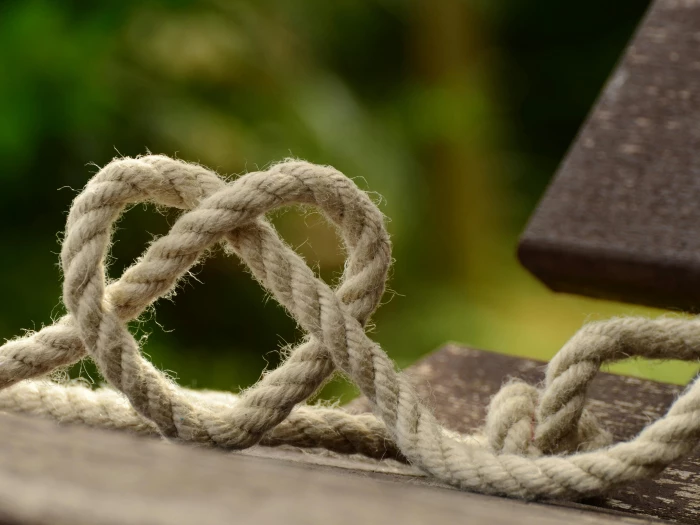 brown rope tangled and formed into heart shape on brown wooden rail