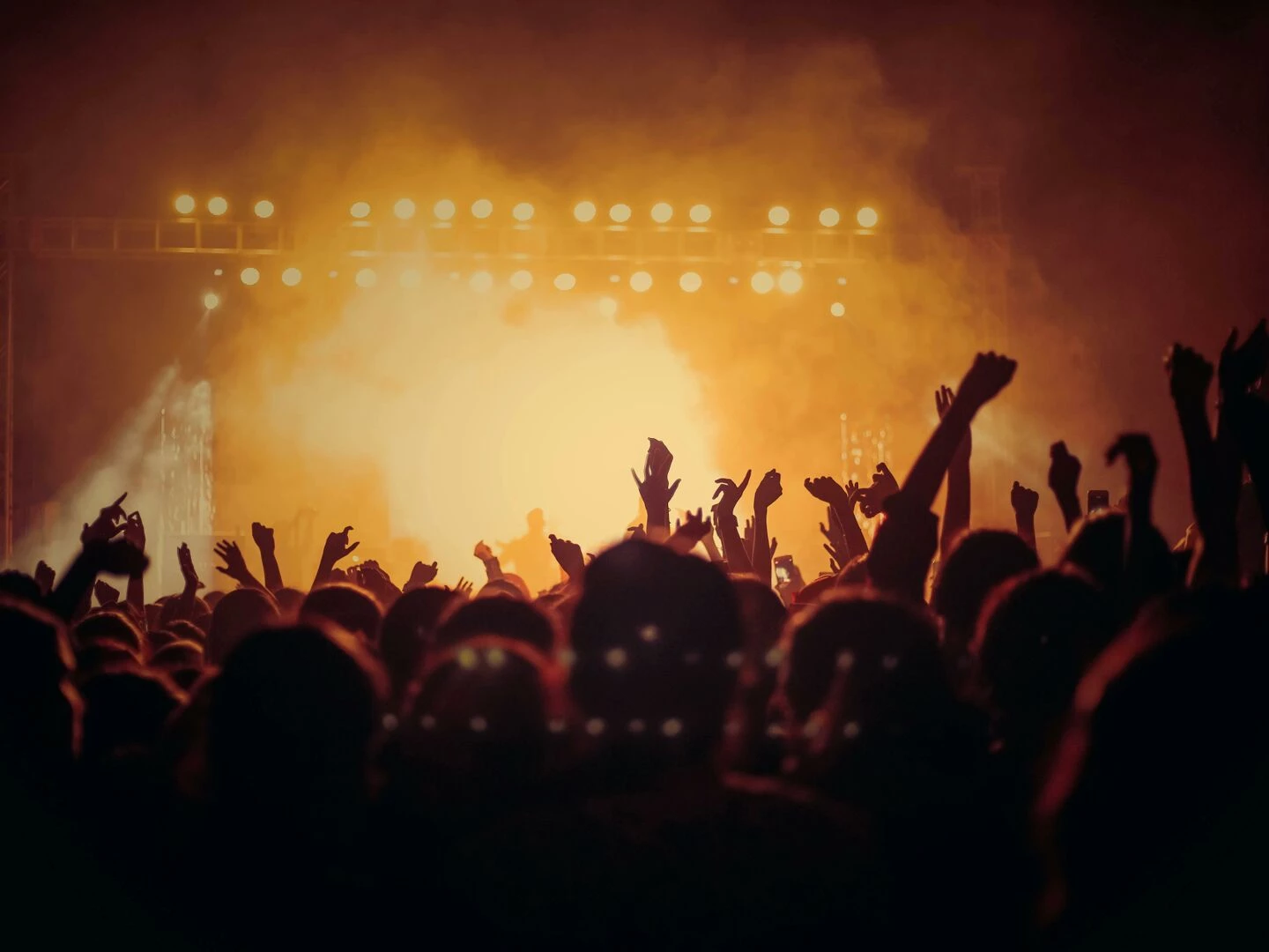 energetic music concert with a vibrant crowd cheering under bright stage lights