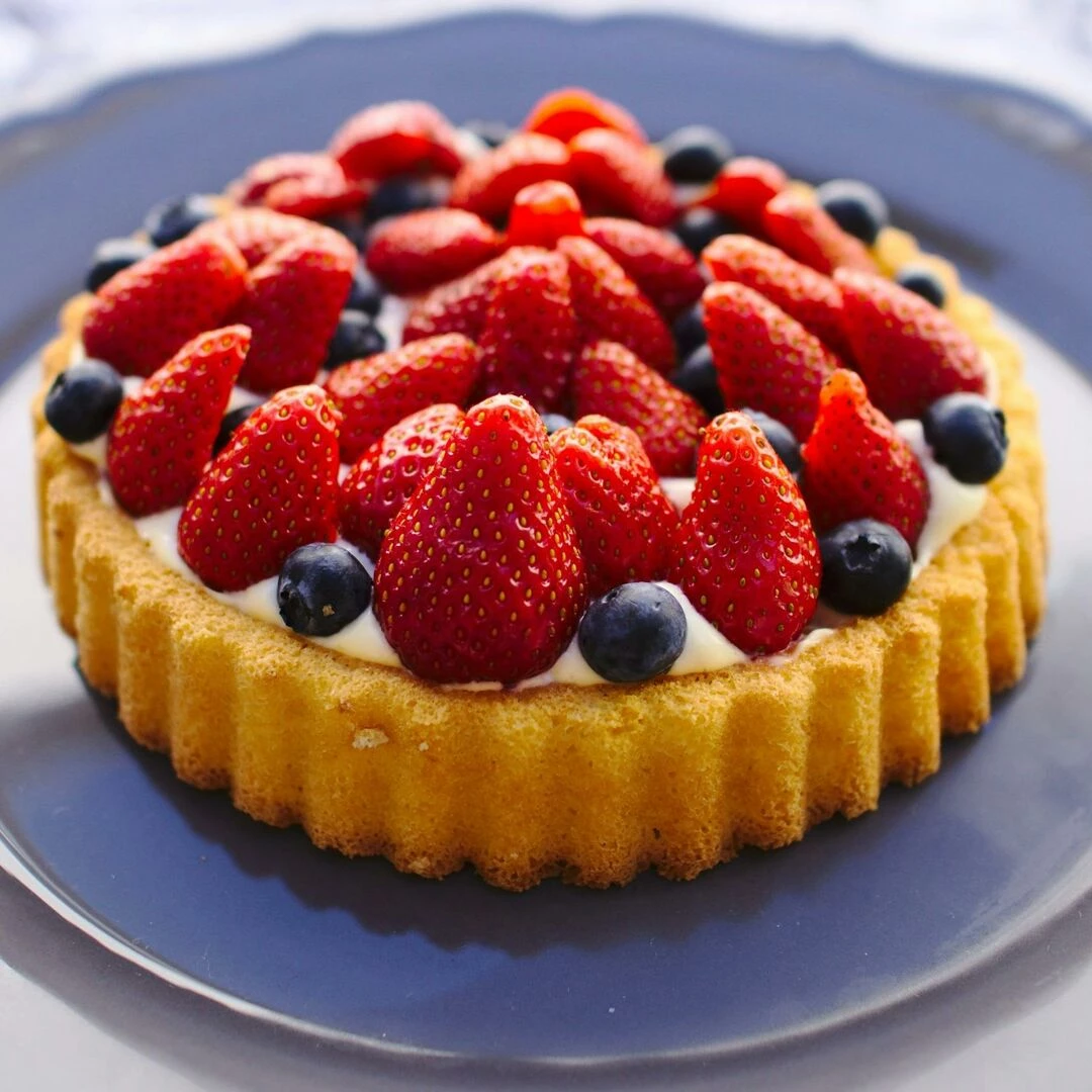 scrumptious homemade fruit tart topped with fresh strawberries and blueberries