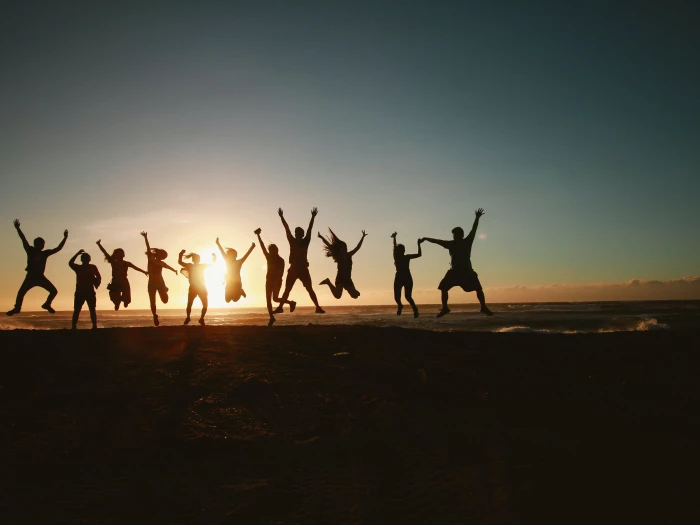silhouette photography of group of people jumping during golden time