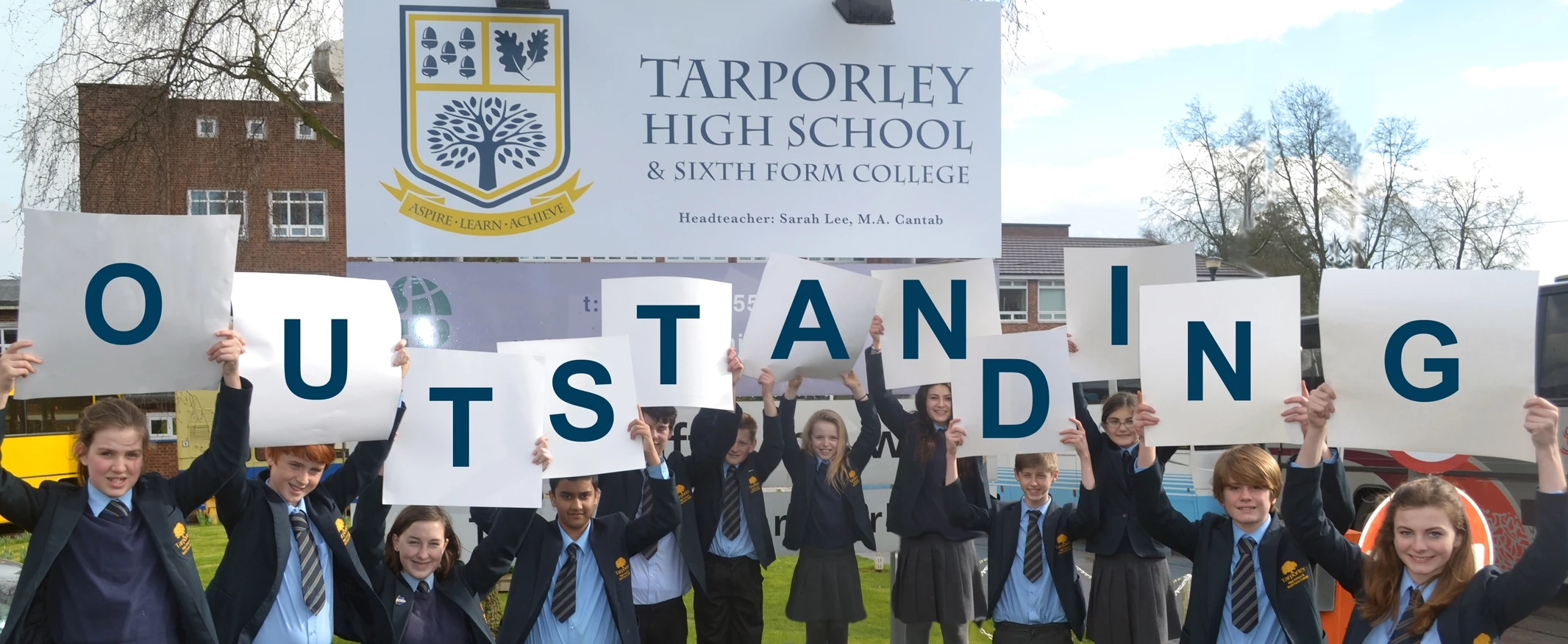 students holding outstanding letters smaller