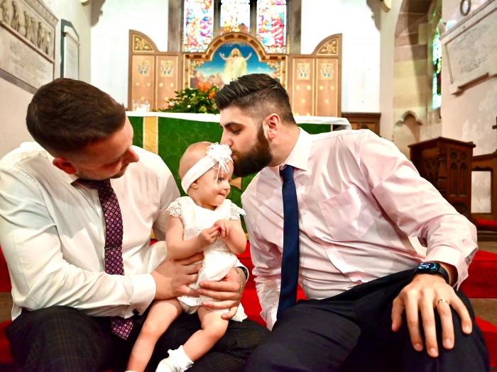 toddler at christening with dad and godfather